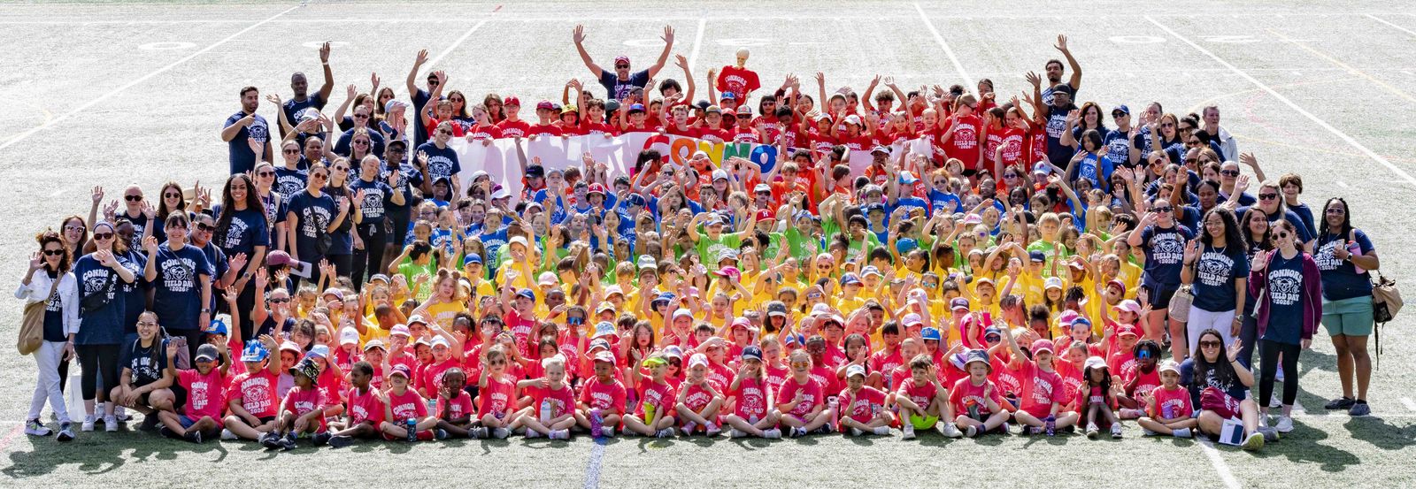The whole school in a rainbow of Field Day shirts, every grade in its color